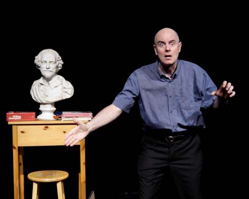 Performer Keir Cutler stands near a bust of Shakespeare