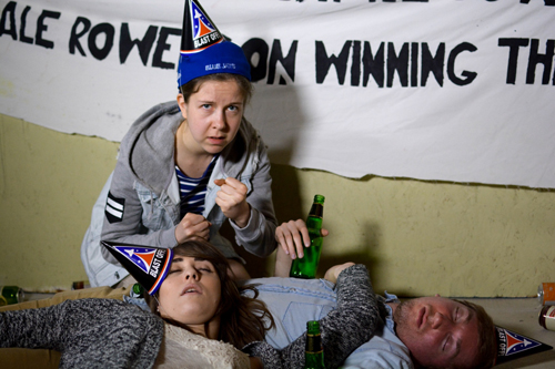 after-party scene, with two people passed out and a third with raised fists