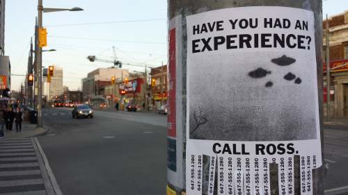 Photo of a poster on a hydro pole asking 'have you had an experience' and showing UFOs