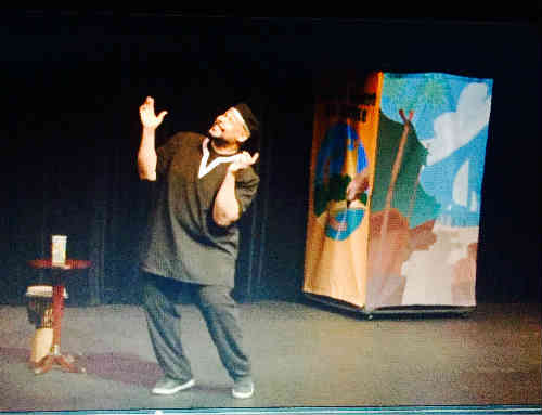 Photo of Anthony Audain and a tropical set piece from the play Tales of Foreign Lands and People.