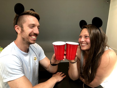Photo of photo of Mike Wisniowski and Kimberly Dolan in BFFs - two smiling friends wearing Mickey Mouse ears toast each other with red solo cups.