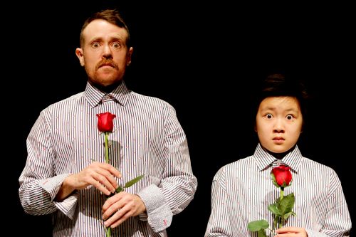 Actors from CHILD-ISH at SummerWorks 2019 A man and a child stand side by side holding long stemmed roses and staring wide-eyed at the camera