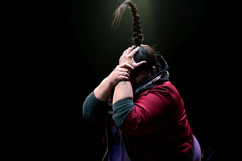 Photo of profile of a woman covering her face with both her hands, her long hair in a braid which stands straight up Yolanda Bonnell in bug