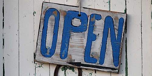 photo of a piece of wood with the word open painted in blue across it